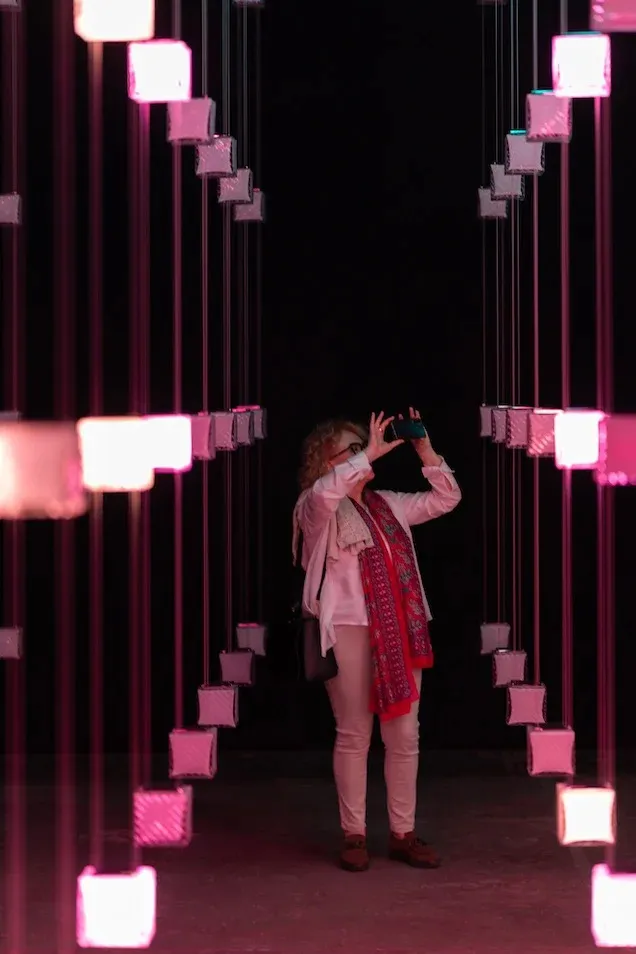 A woman takes a photo in an interactive light installation.