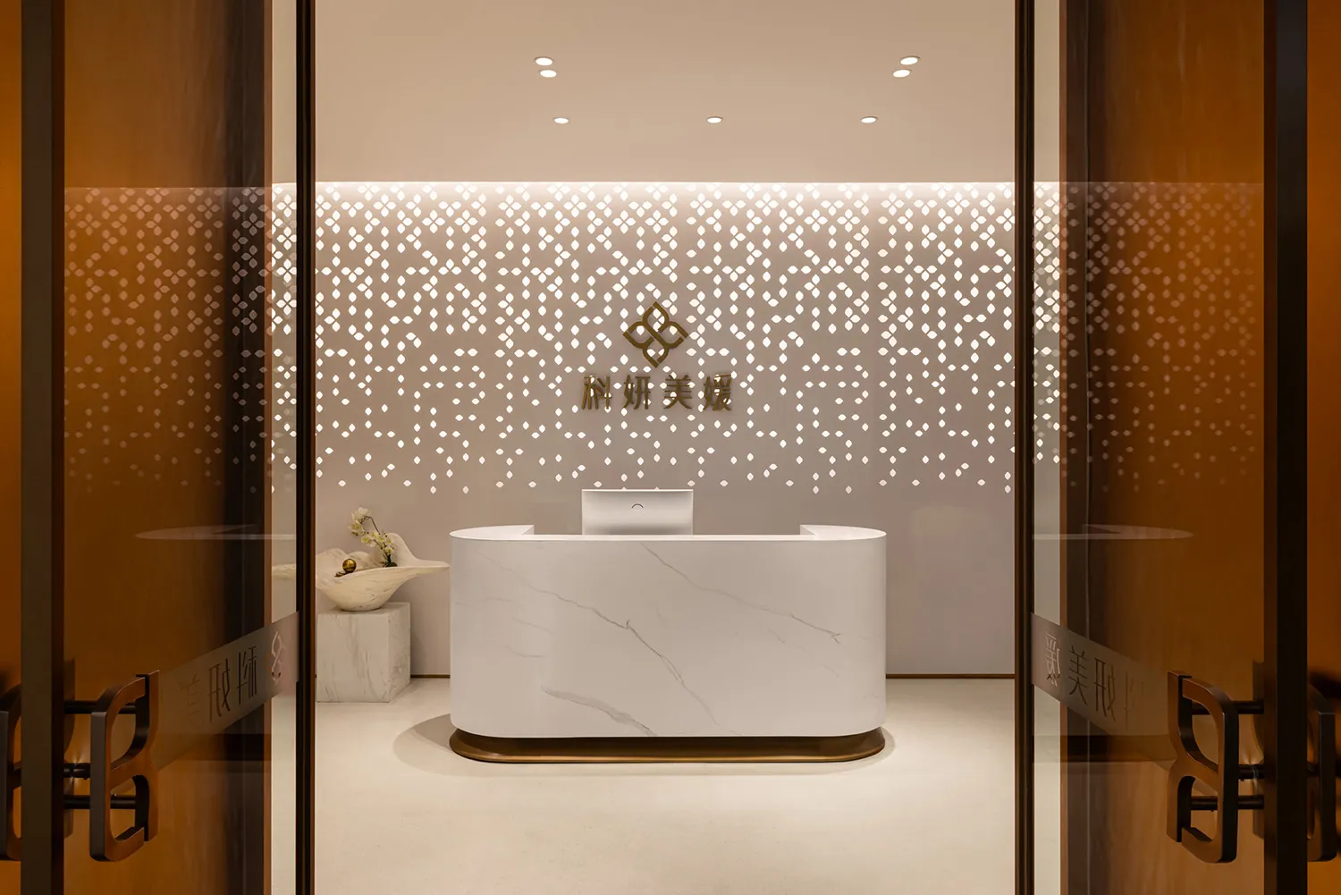 Modern lobby interior with marble reception desk and illuminated wall behind it.