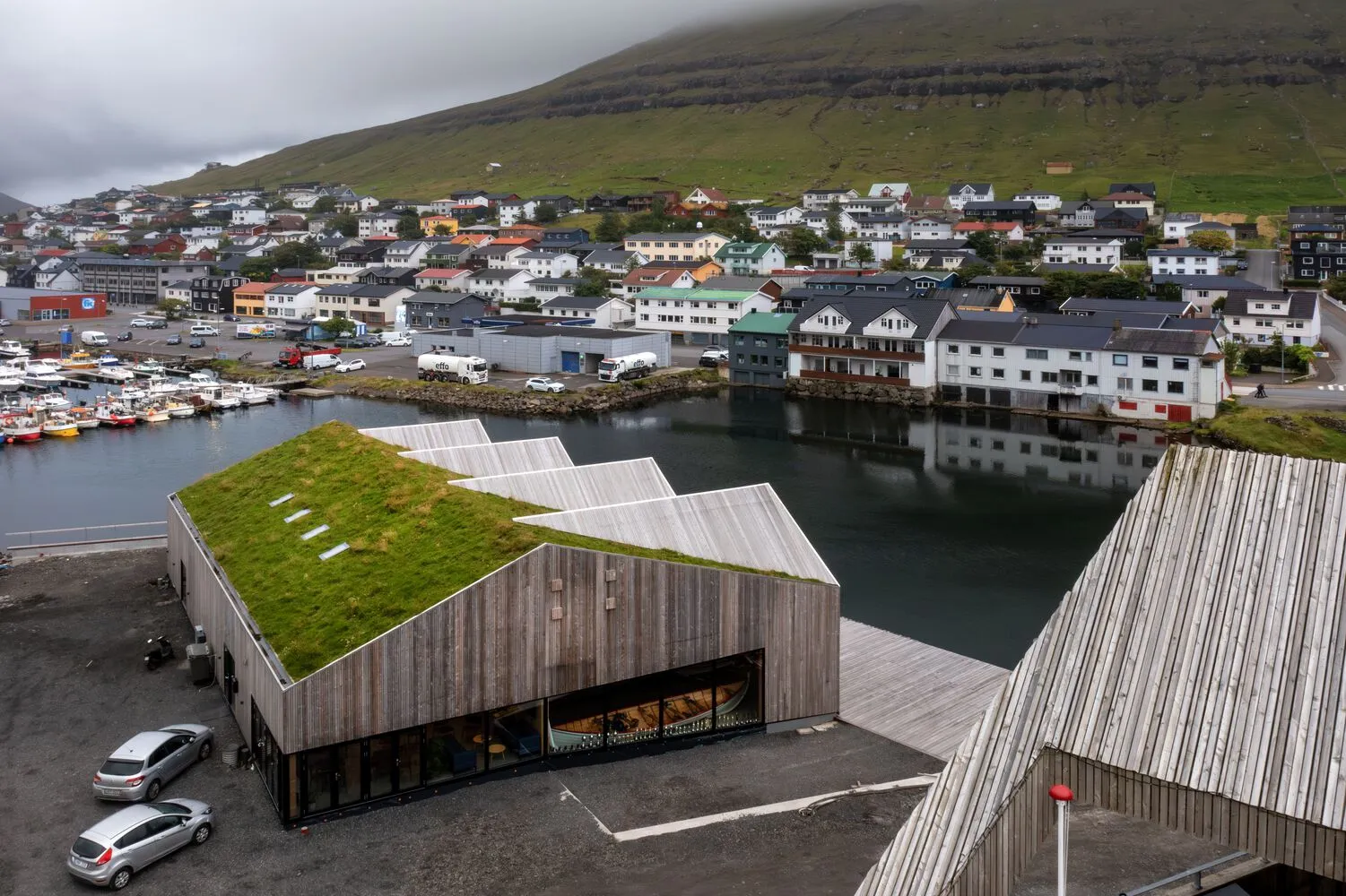A modern urban design featuring a wooden roof above a body of water.