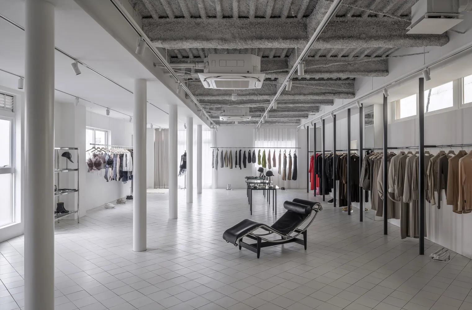 A modern retail shop featuring a concrete ceiling and clothing racks.