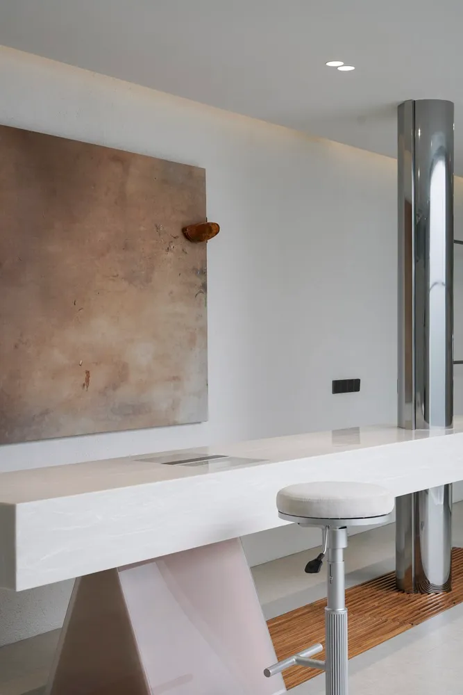 Modern white bar stool with a sleek, minimalist design next to a contemporary white kitchen counter top with a polished finis