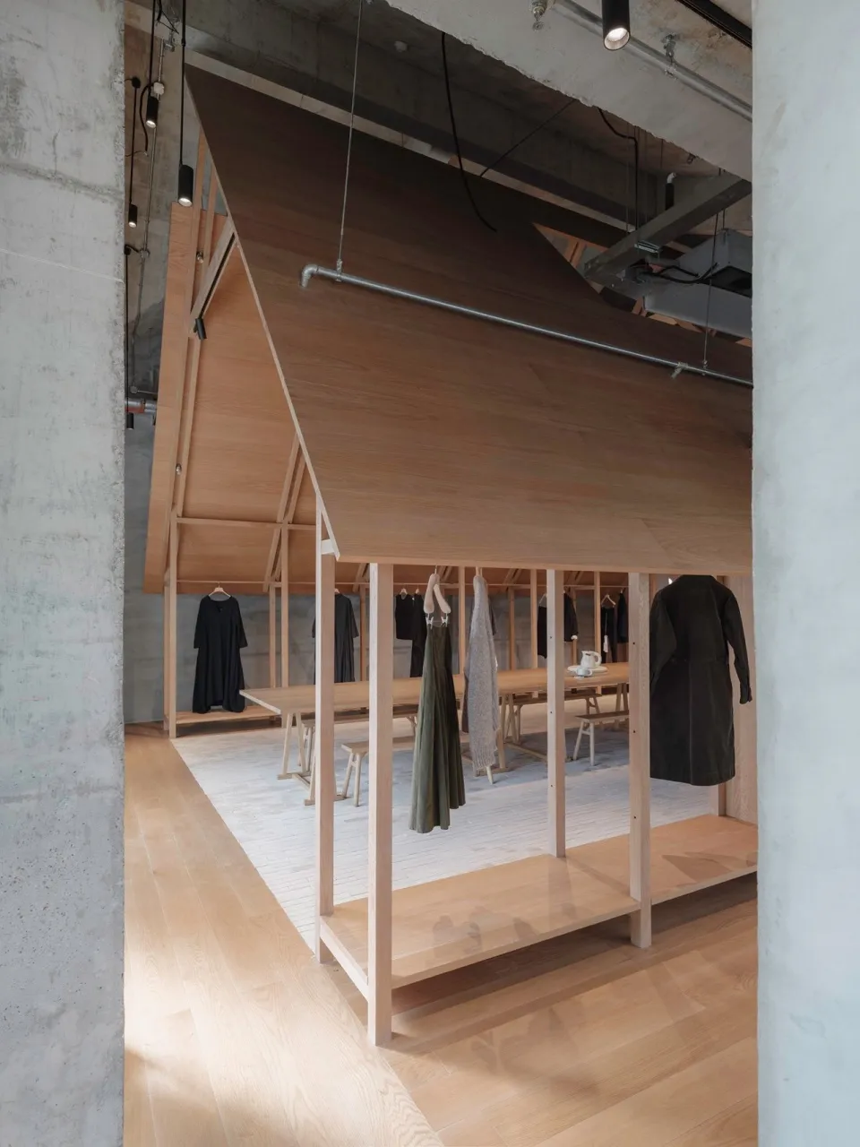 極簡服飾店內部,木質牆面與地板,陳列服裝展示架。