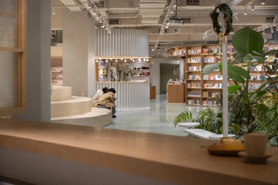 A modern library interior with wooden shelves, concrete steps, and glass elements.
