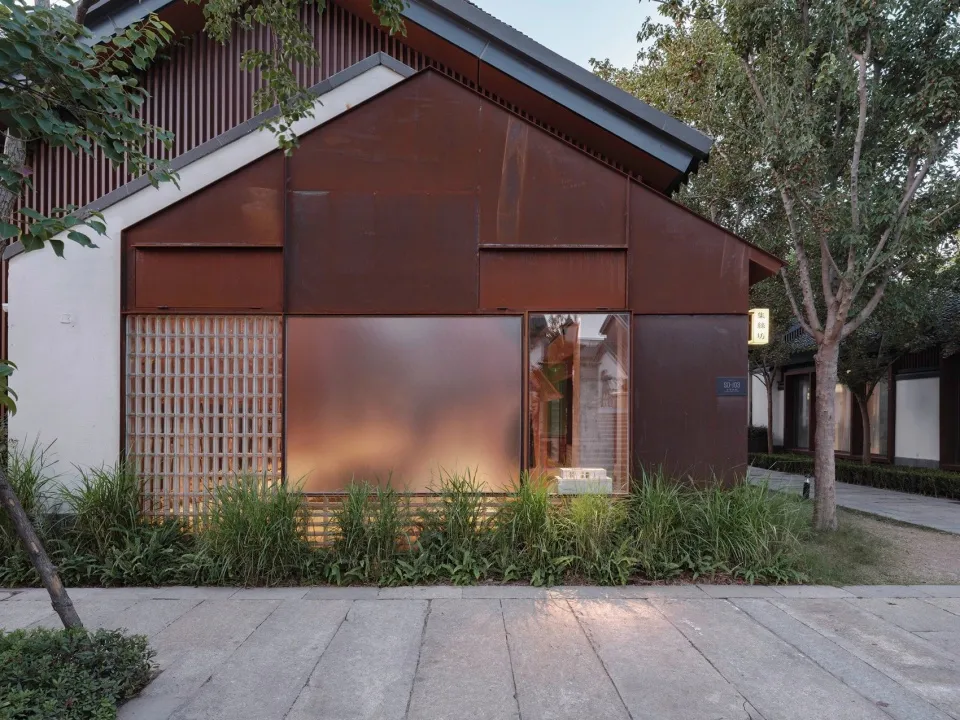 Rustic storefront with glass doors and metal facade in an outdoor setting with trees.