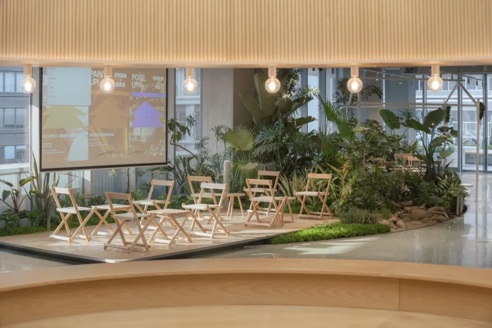 An industrial-style coffee shop with wooden furniture and greenery on a stage-like platform.