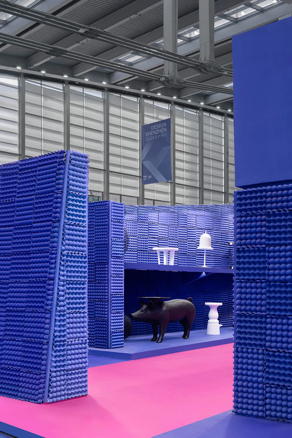 Industrial design exhibition featuring blue plastic foam blocks and a black ceramic animal