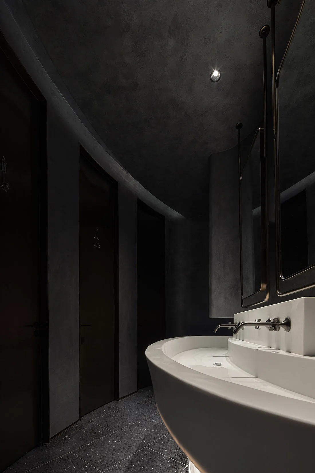 Modern industrial black and white bathroom with curved white sink and large mirror