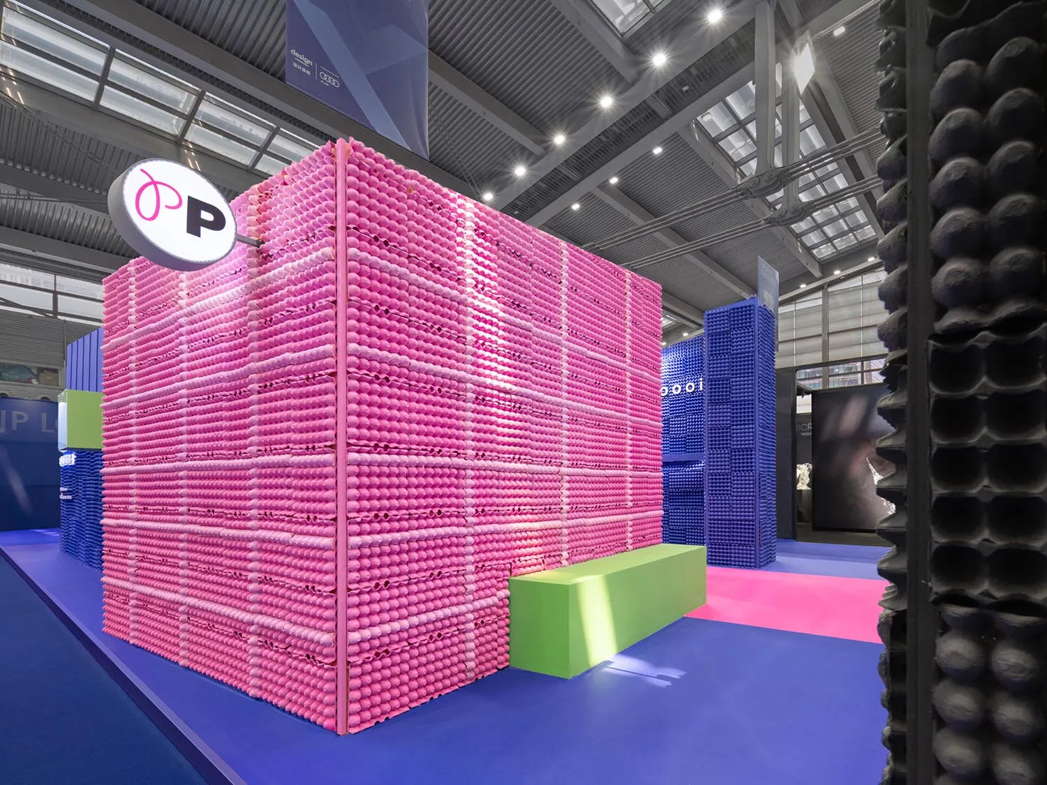 A modern exhibit installation made predominantly of pink and blue plastic objects arranged in a cube shape.
