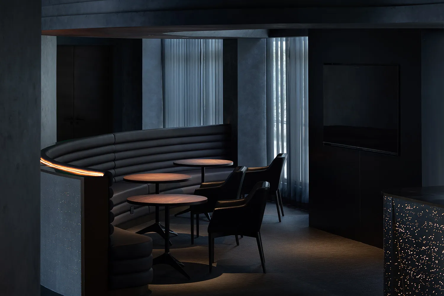 現代設計的座位區,配有圓桌和黑色皮革椅,置於餐廳/咖啡廳環境中。