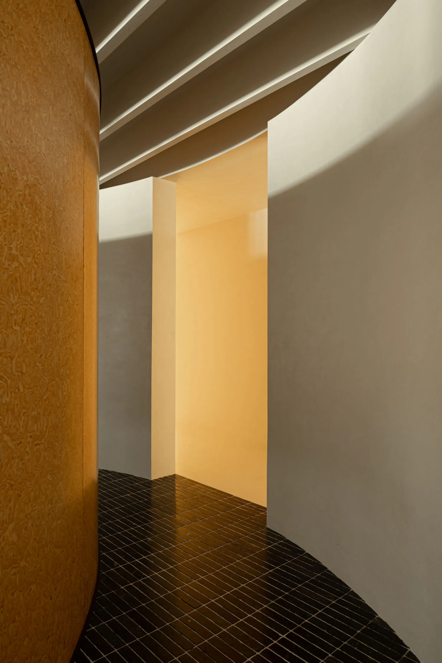A minimalist interior space with sandblasted concrete walls and a dark tiled floor.