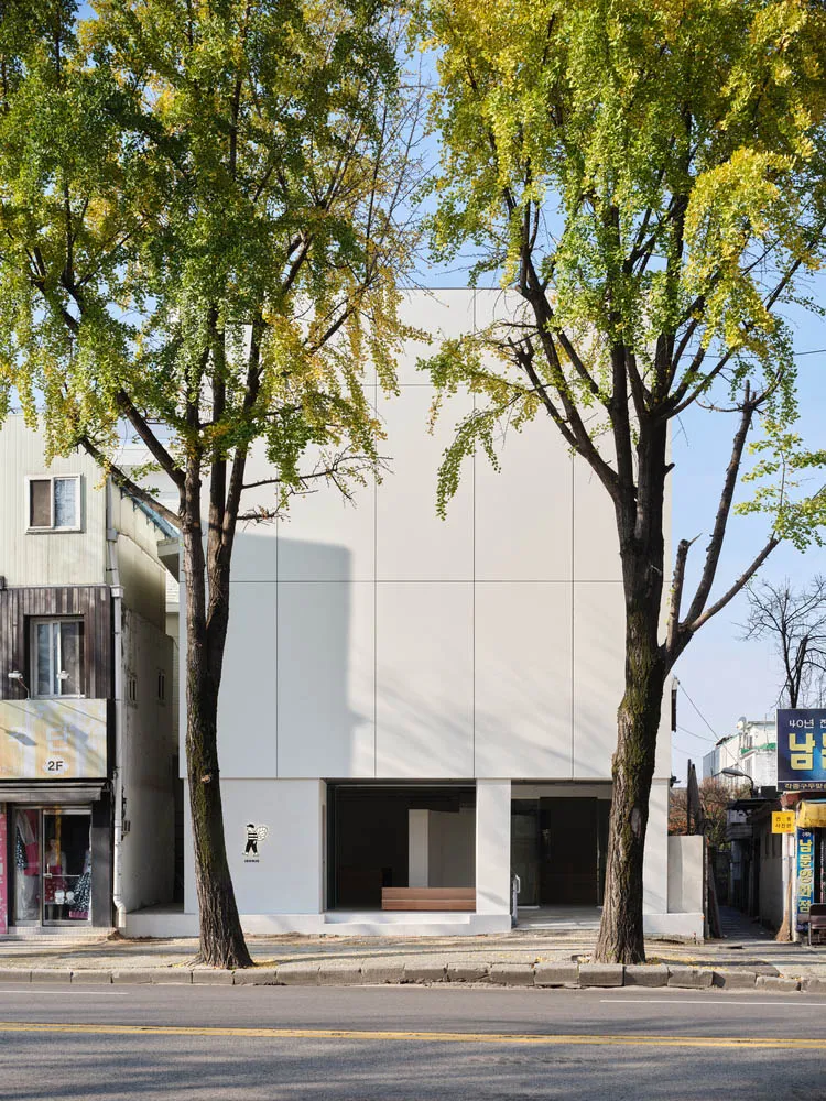 一座現代零售店面,擁有白色粉刷的混凝土外觀。