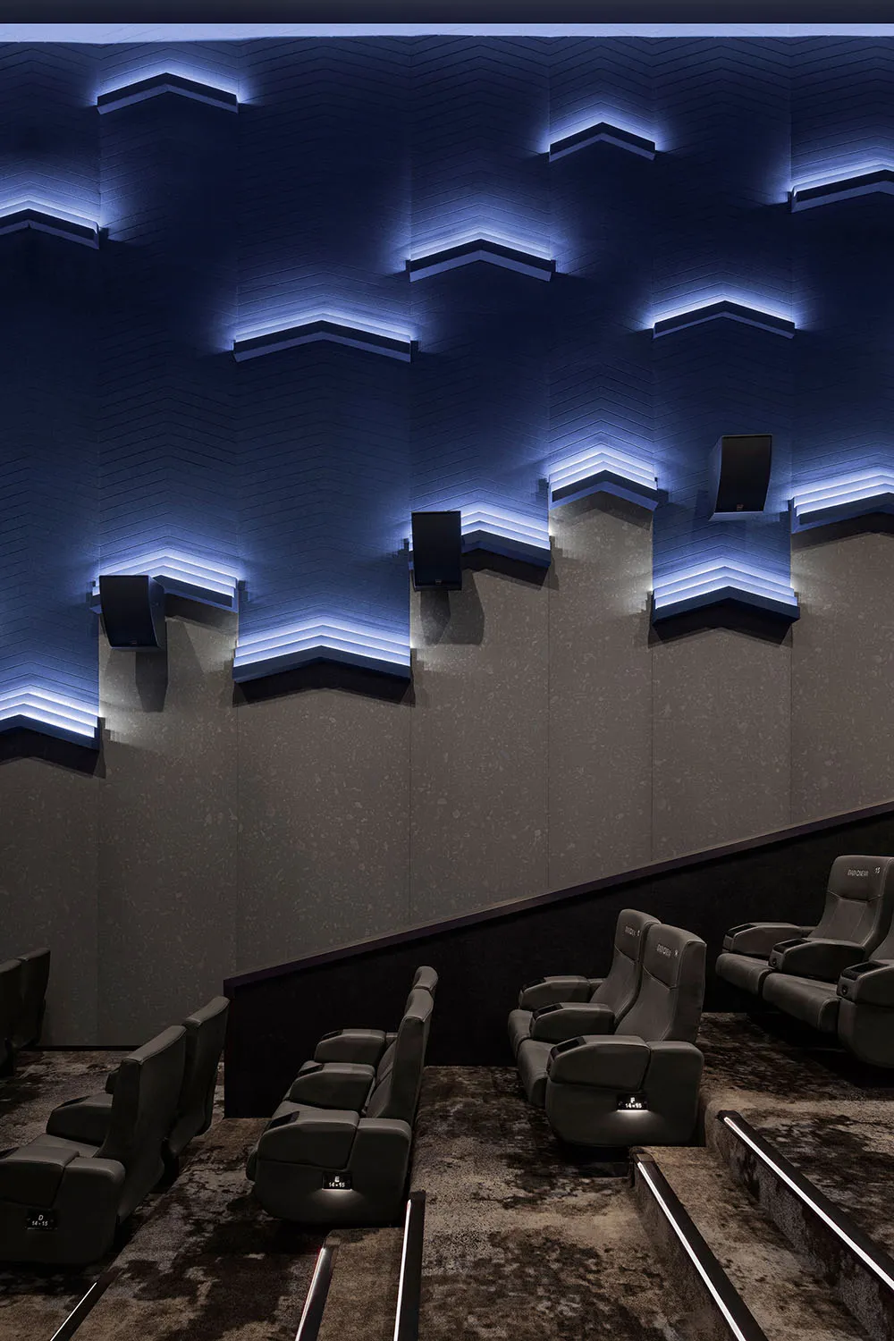 Industrial-style cinema interior with textured concrete walls and modern, ergonomic seating.