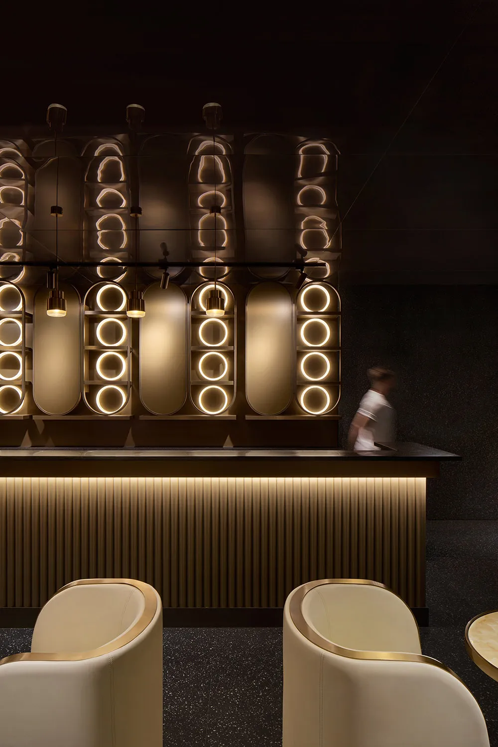 A sleek, modern bar area with metallic finishes and circular lighting fixtures.