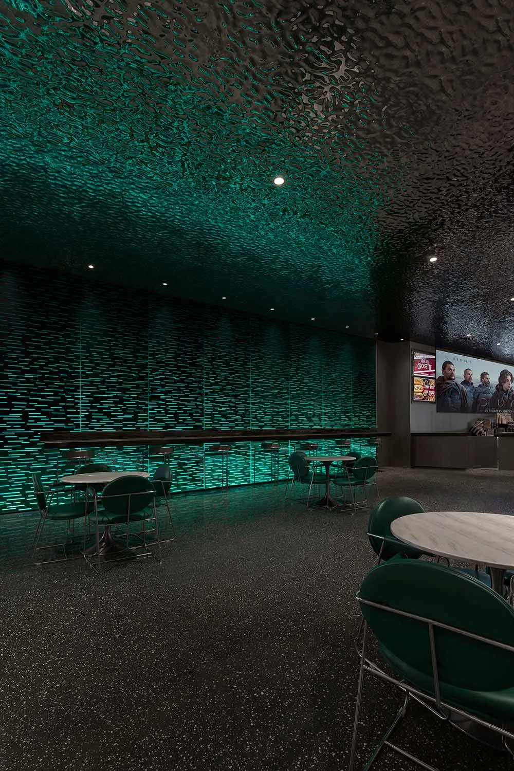 A modern restaurant bar with a textured concrete ceiling and green lighting.