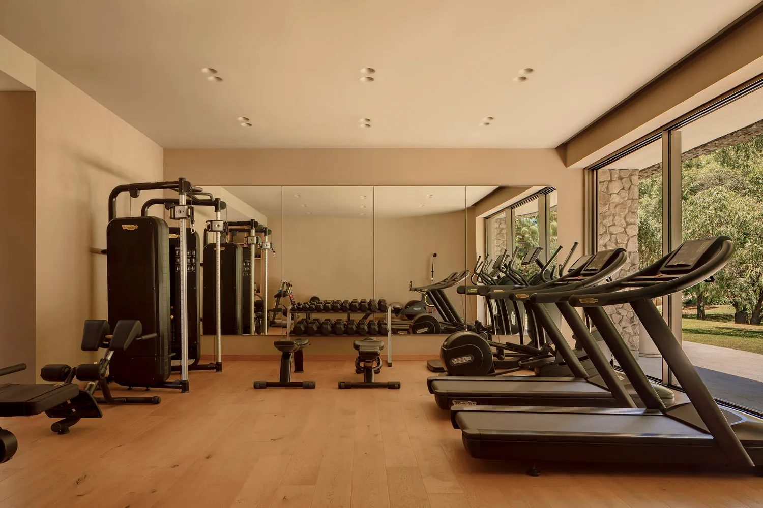 A modern exercise room featuring wooden flooring and various fitness equipment.