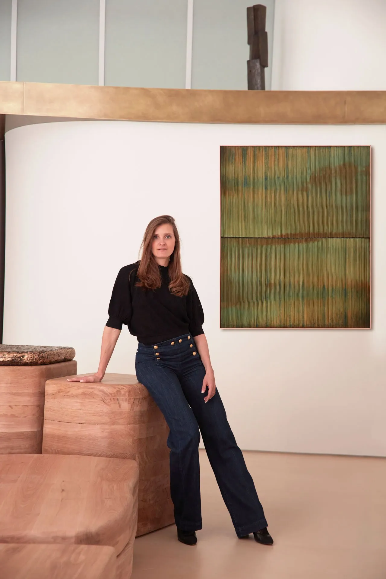 Woman standing in a modern art gallery with a contemporary artwork on the wall.