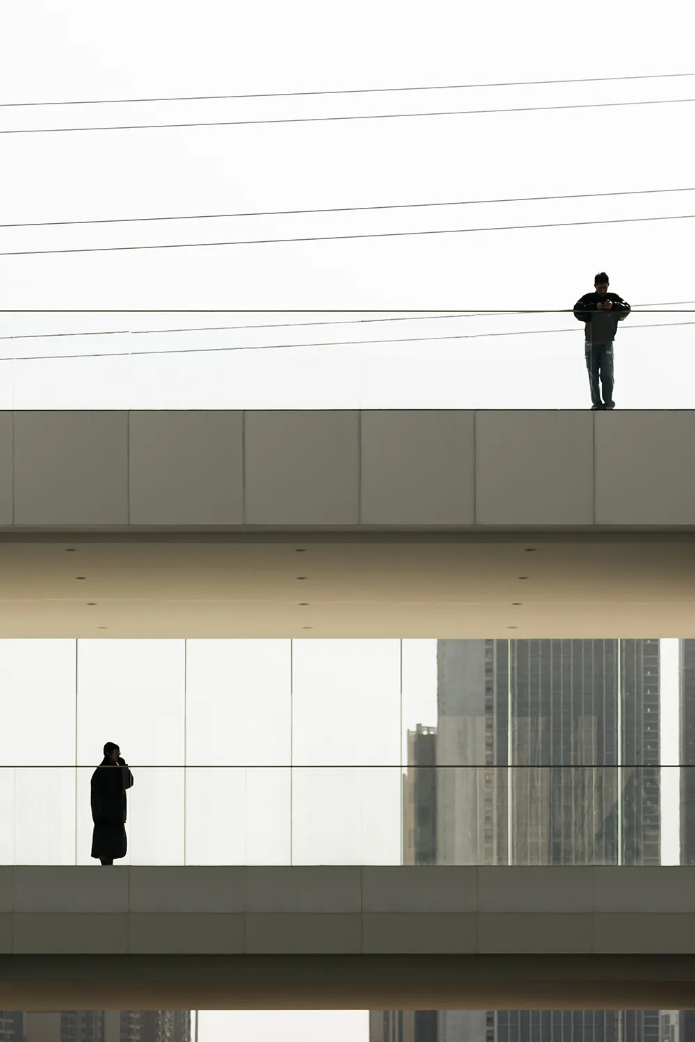 A modern glass bridge features architectural designs with urban infrastructure visible in the background.