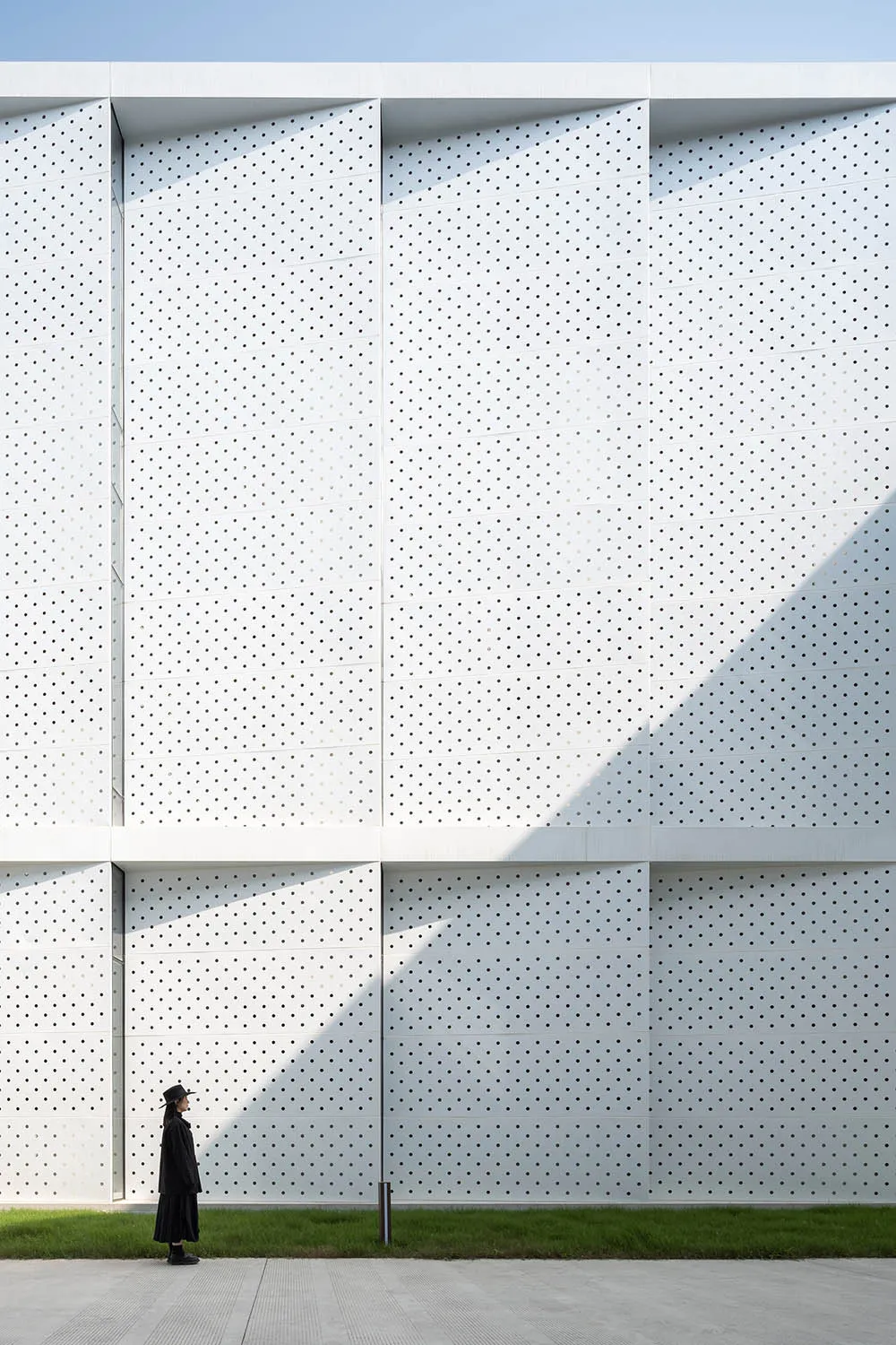 A modern building facade featuring a white perforated metal panel