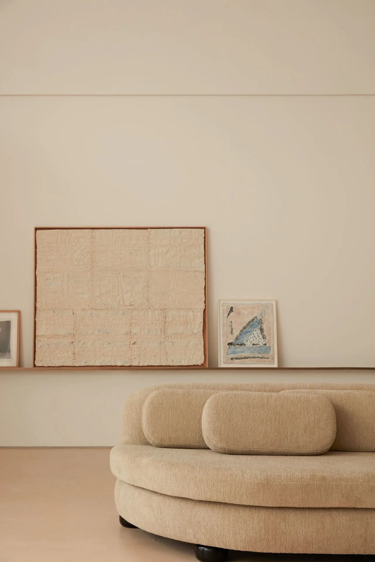 Modern circular sofa with neutral fabric upholstery against a minimalist backdrop with abstract artwork.