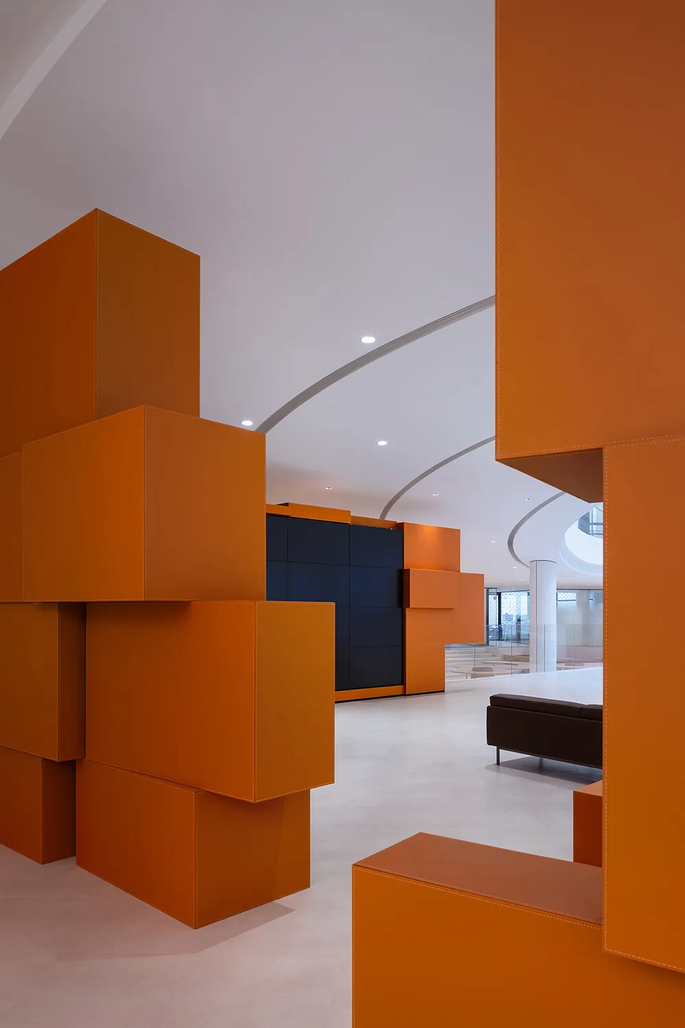 A modern office space featuring orange cube structures, white walls, and a concrete floor.