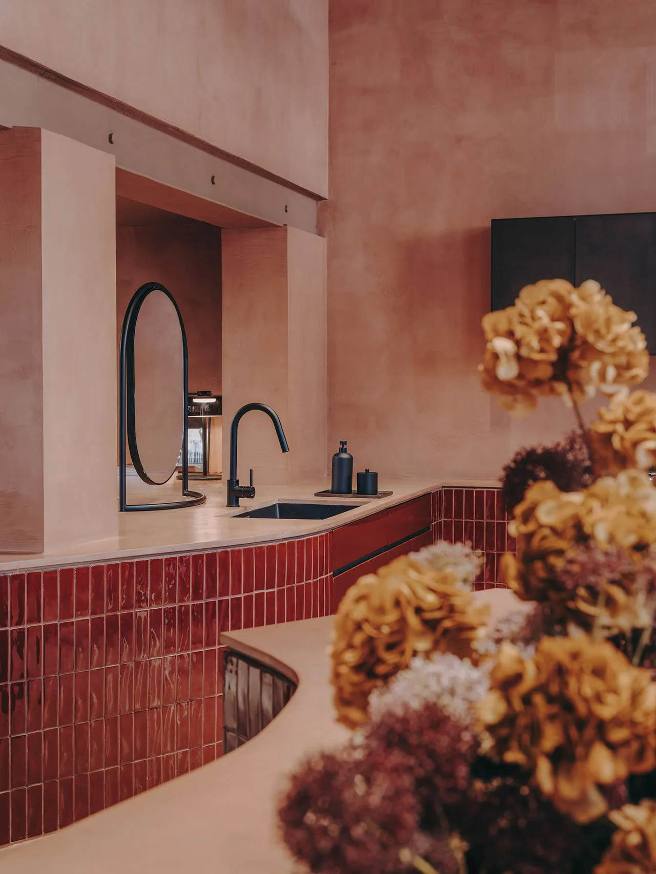 A minimalist bathroom featuring red ceramic tiles and black fixtures