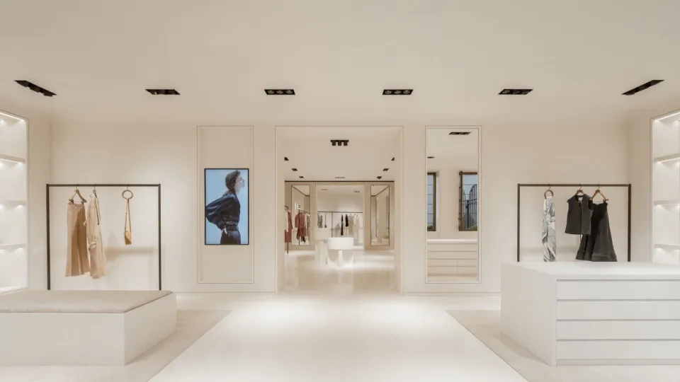 Interior of a minimalist clothing retail store with neutral-colored materials and a central display area.