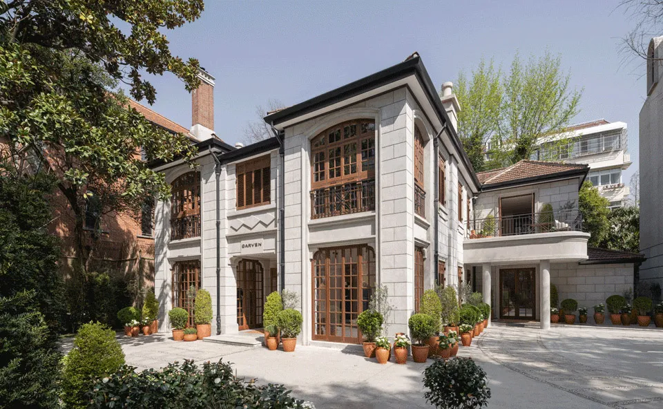 A modern residential home with a white mortar blocks and red brick front yard entry area with multiple potted plants and gree