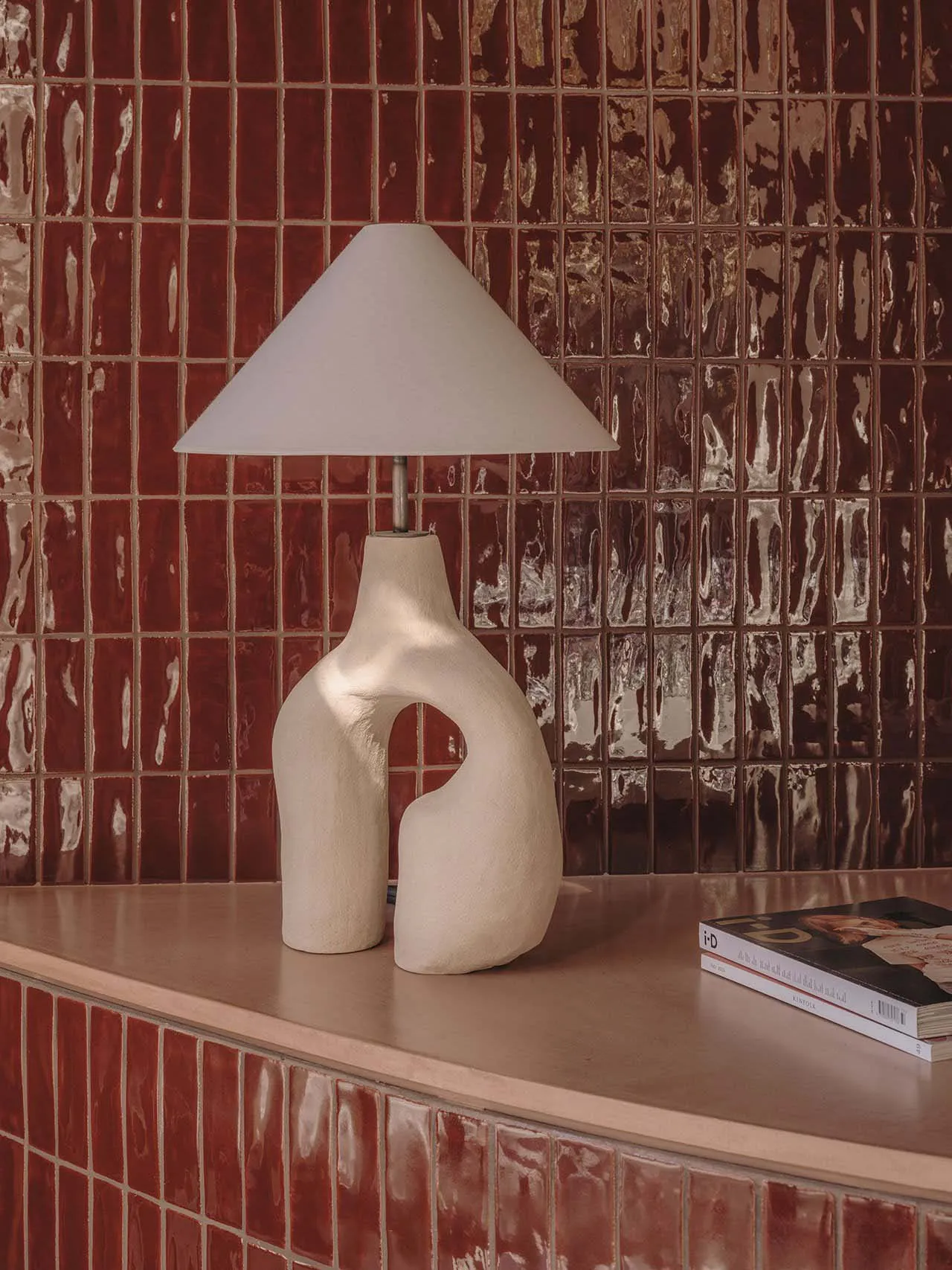 A modern, abstract ceramic lamp with a conical shade in a living room setting.