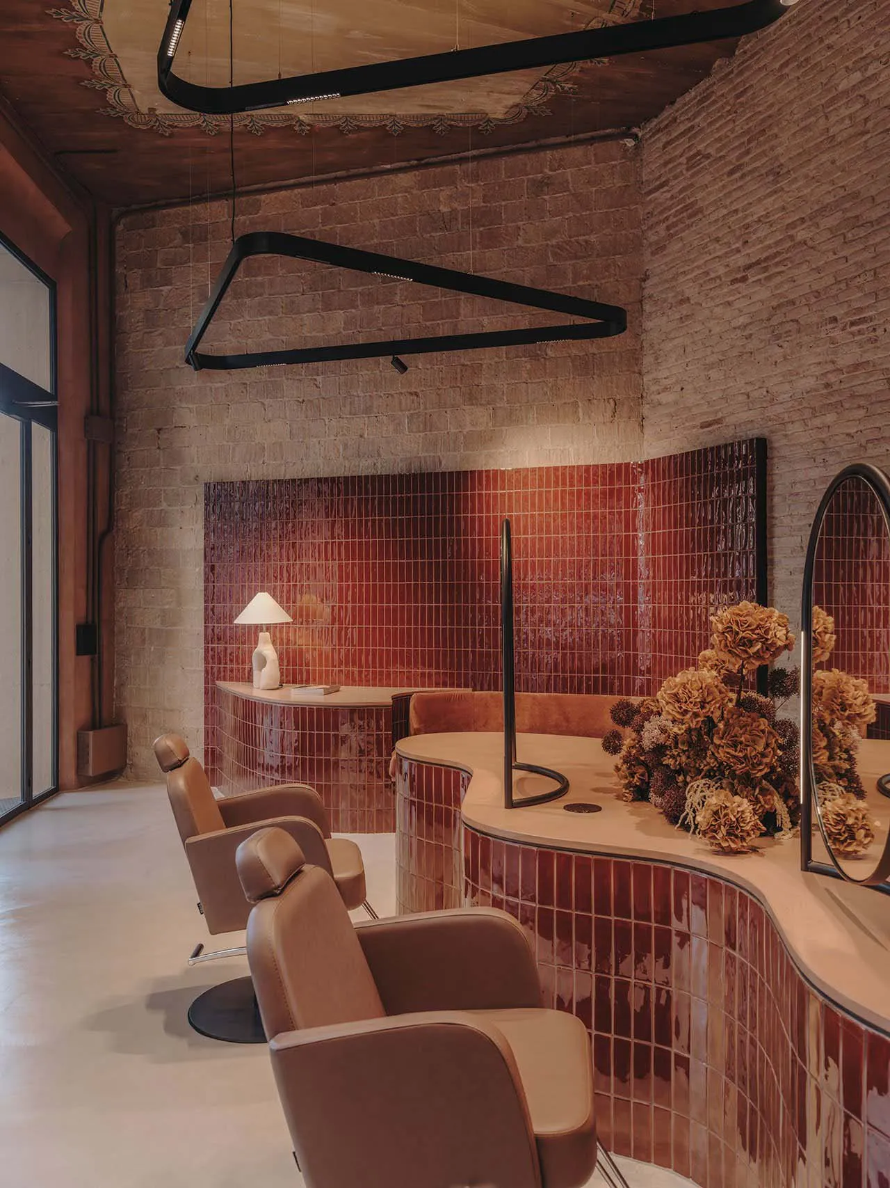 A modern salon interior featuring sleek, red ceramic tiles and elegant seating.