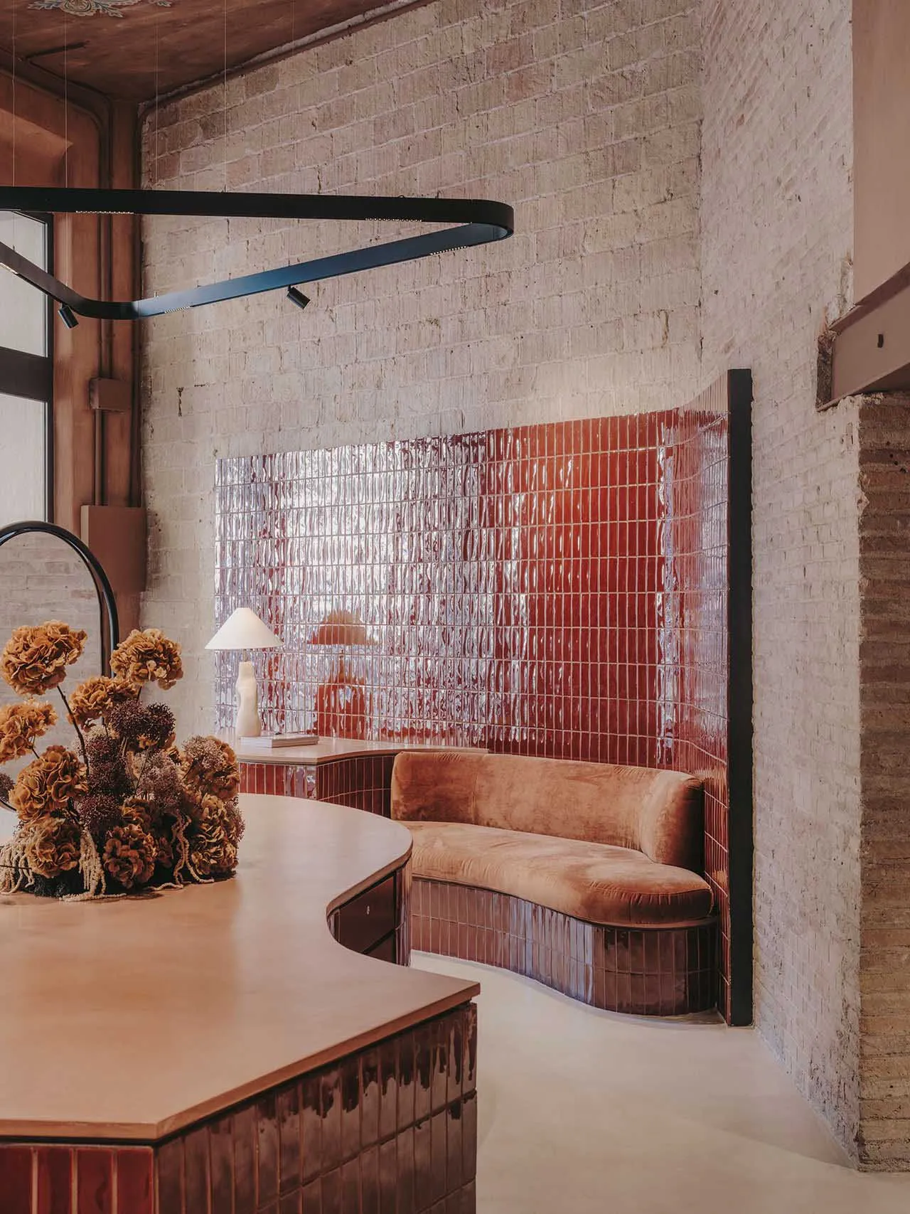 Industrial-style coffee shop interior featuring brick tiles and curved seating.