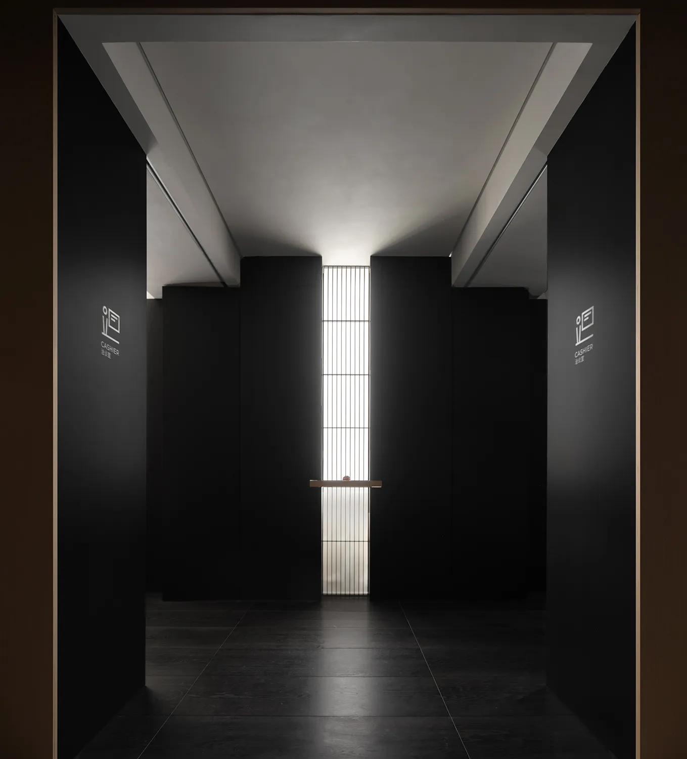 A minimalist commercial hallway with black panels and a high ceiling.