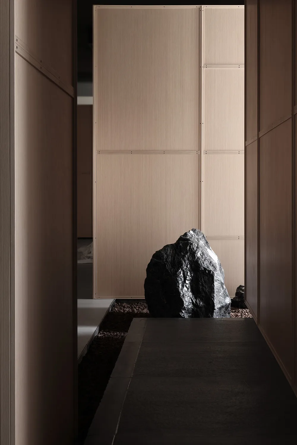 A modern corridor with a large boulder and concrete floor.