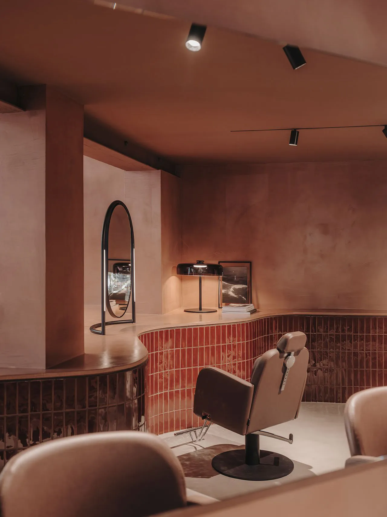 An interior photograph of a modern hair salon featuring a hair styling chair and red-tile accents.