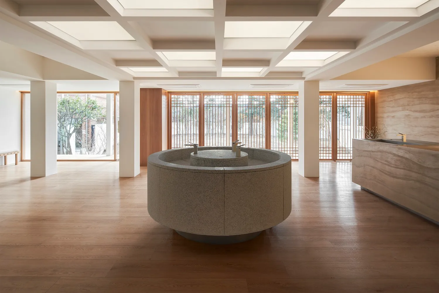 Modern hotel lobby with natural stone flooring and a circular central feature.