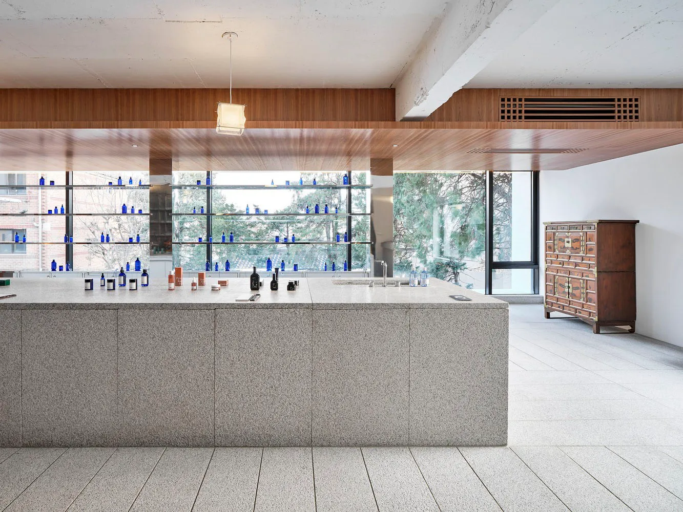 A modern retail storefront featuring a marble counter with bottles and vials displayed on shelves.