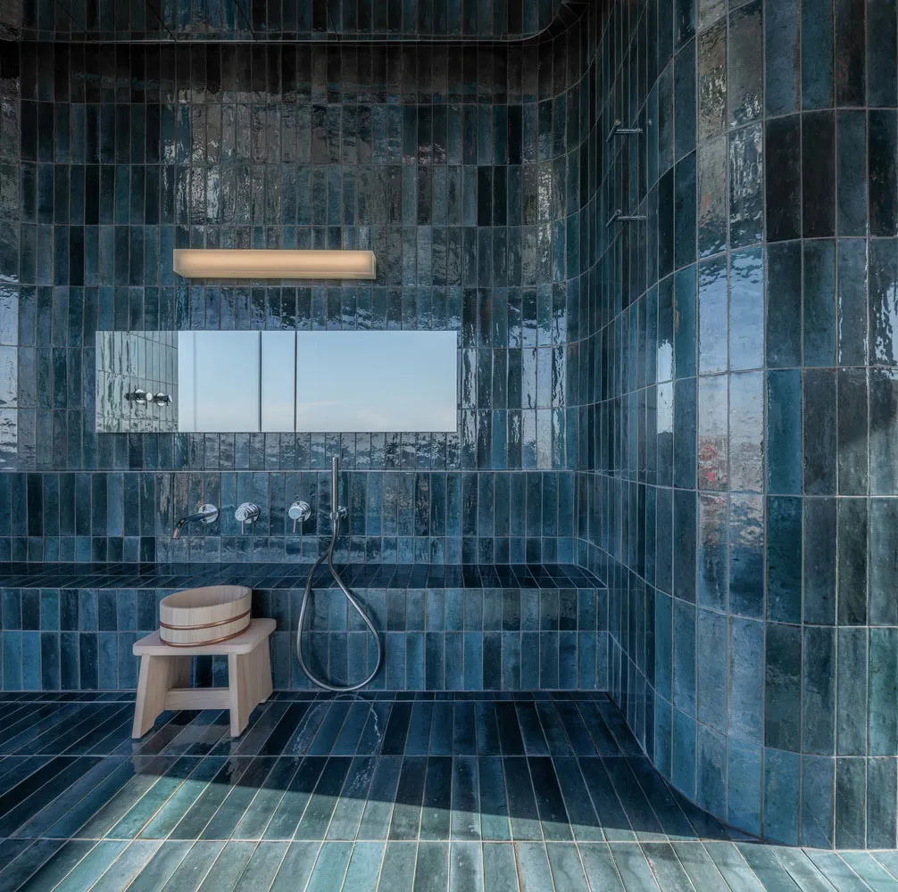 Industrial-style bathroom interior with blue-tiled walls and floor, minimalistic design, and functional fixtures.