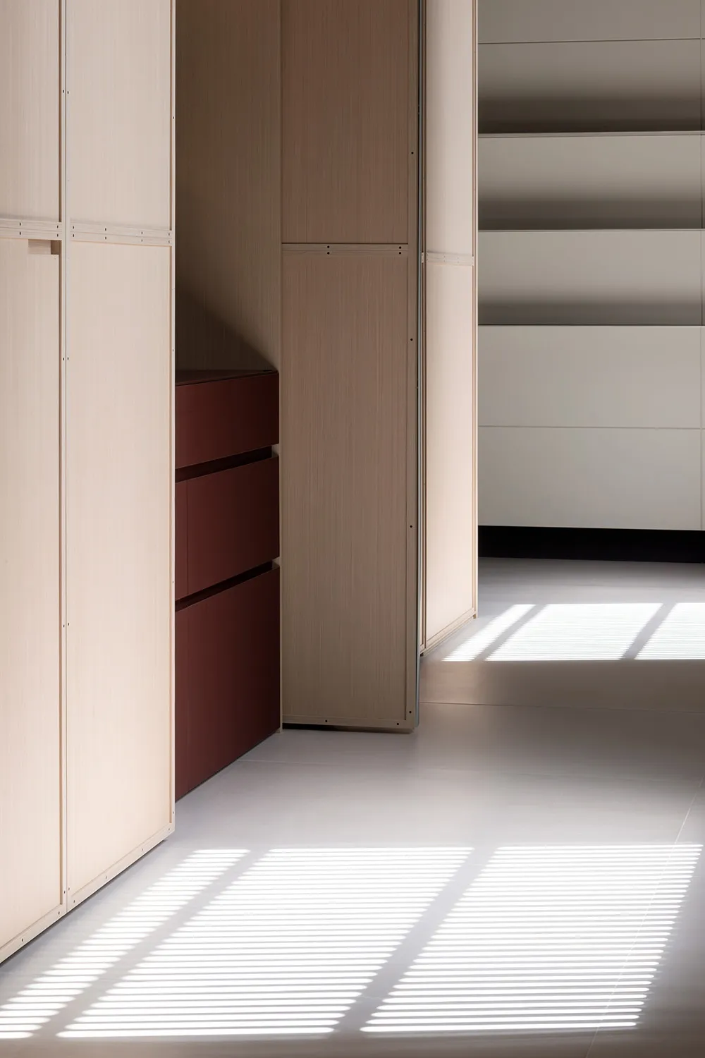 A minimalist closet interior with light wooden cabinets and drawers.