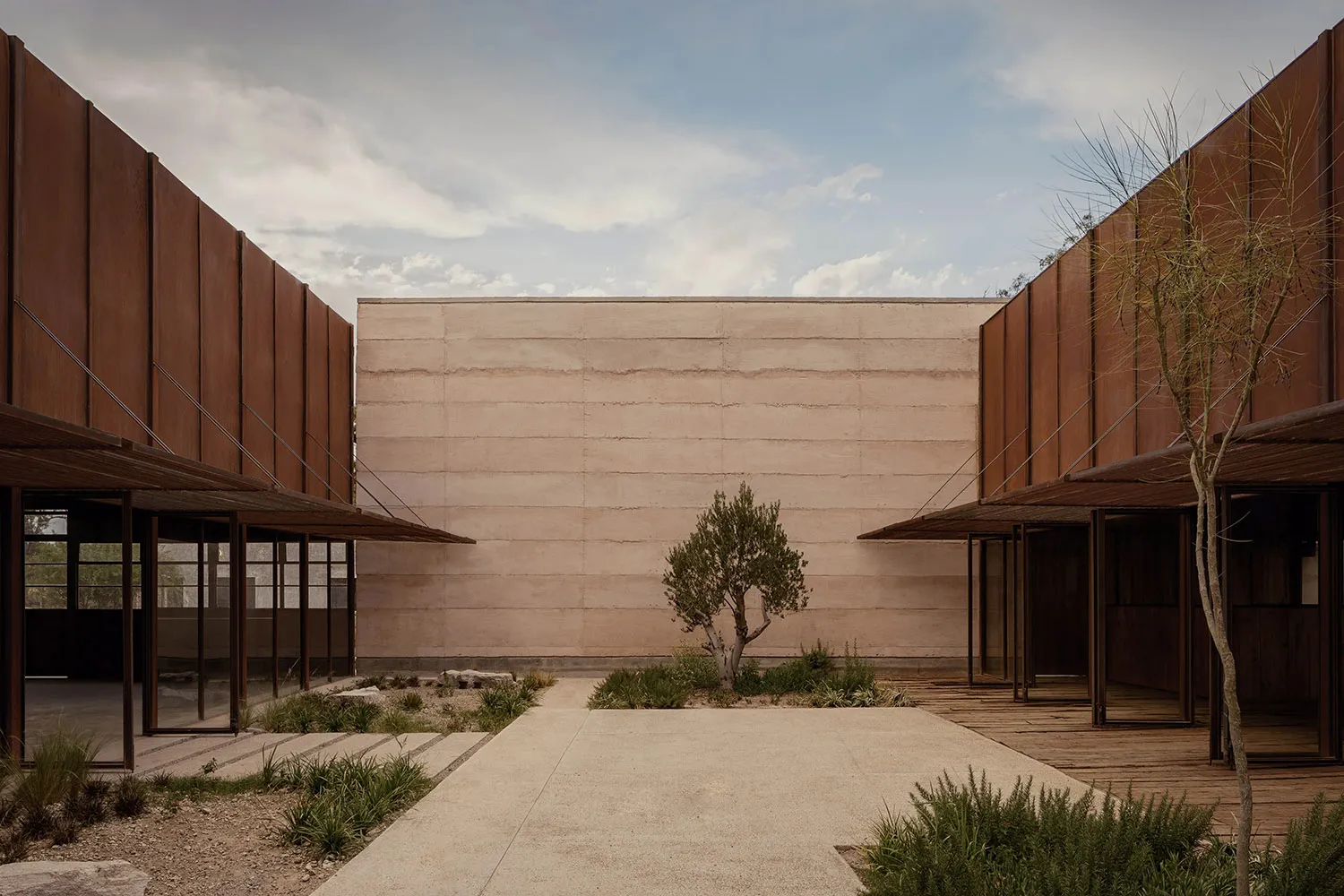 A minimalist building entrance with a concrete wall and pathway leading to the entrance door.