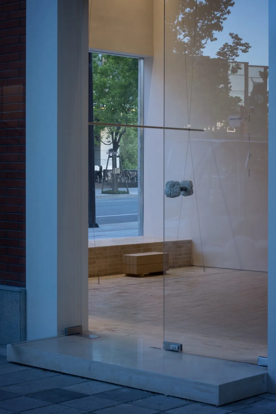 A modern storefront with glass walls and a wooden bench