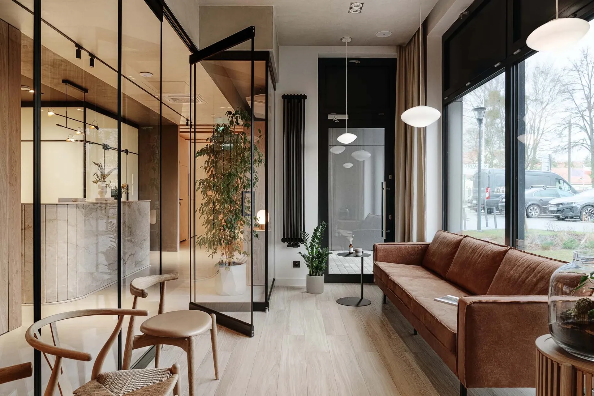 Modern living room with a marble floor and wooden furniture, featuring a brown leather sofa and potted plants.