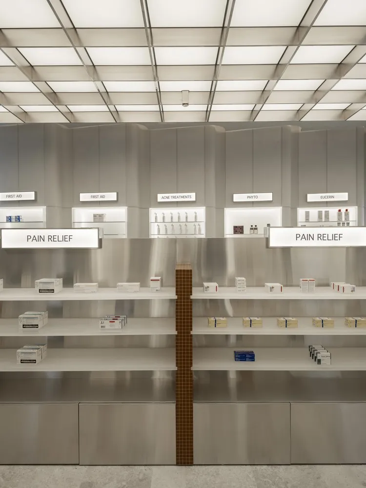 Empty shelves in a modern pharmacy interior with metallic walls and signage.