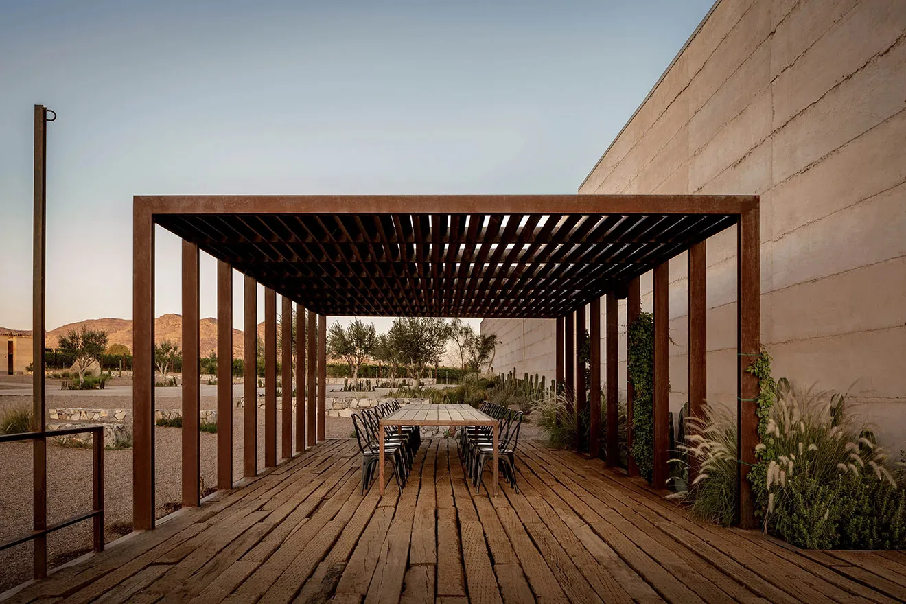 A modern patio area with wooden flooring, a wooden pergola, and seating for eight people.