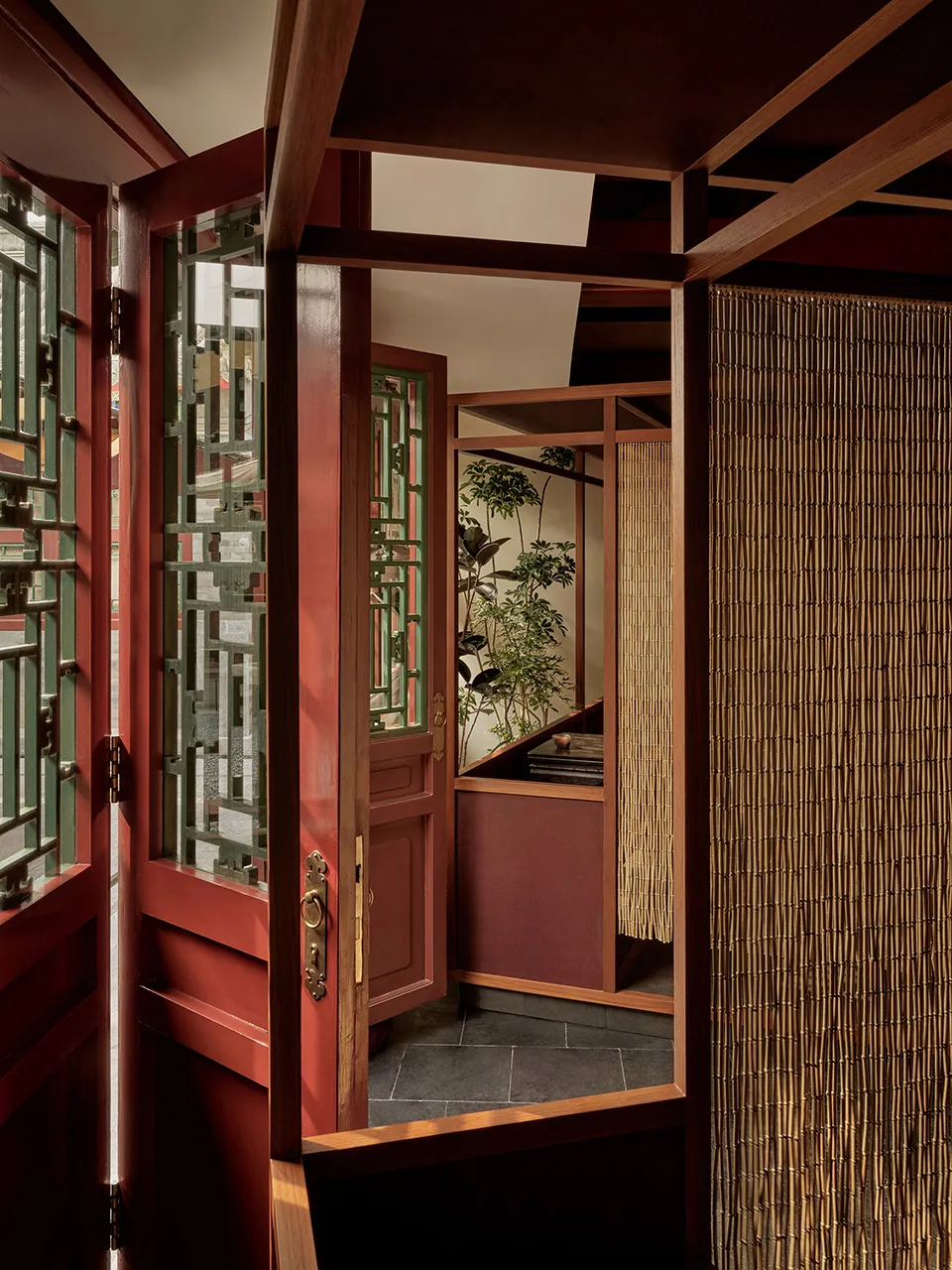 Traditional wooden framed entrance hall interior with bamboo curtain and greenery.