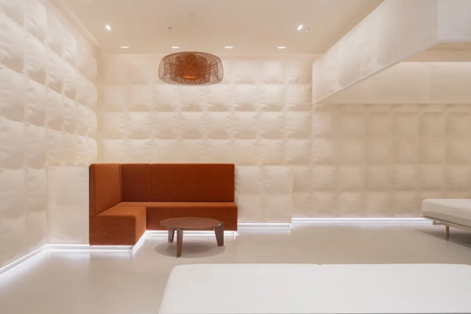 A minimalist hotel suite with white and neutral fabrics in a contemporary design.