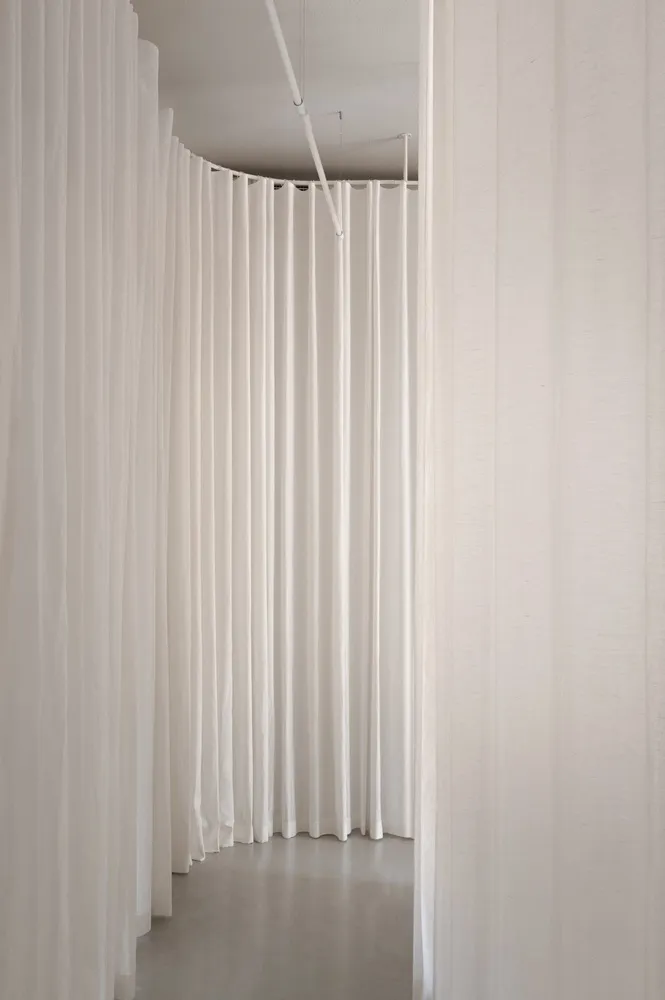 A minimalist installation featuring hanging white fabric panels.