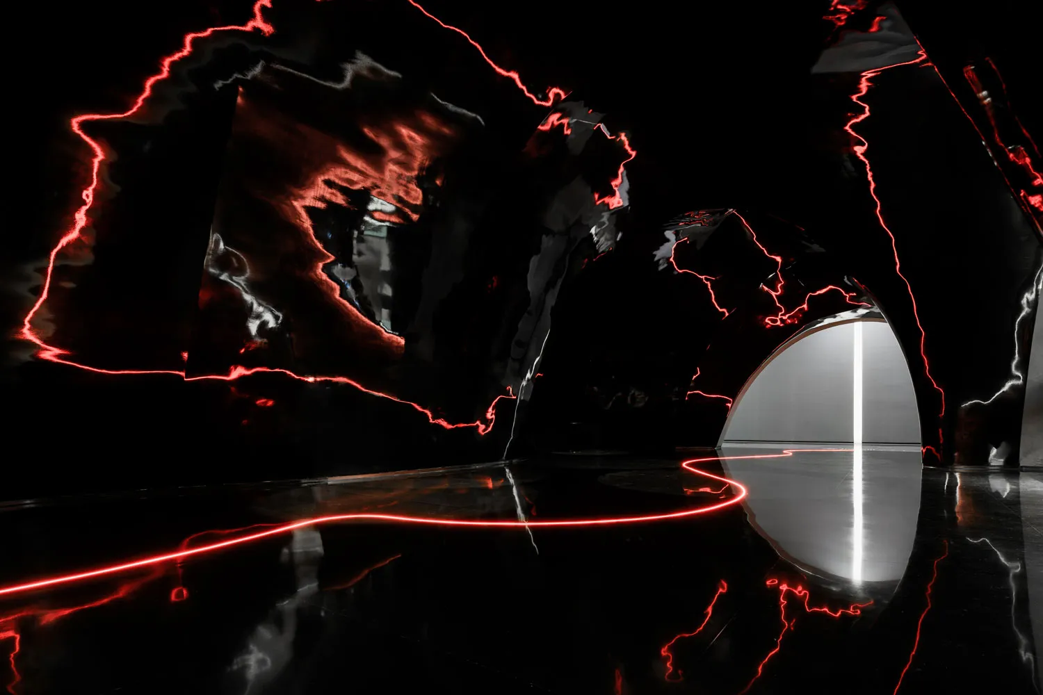 A modern art installation featuring bold, red laser light patterns against a dark background.