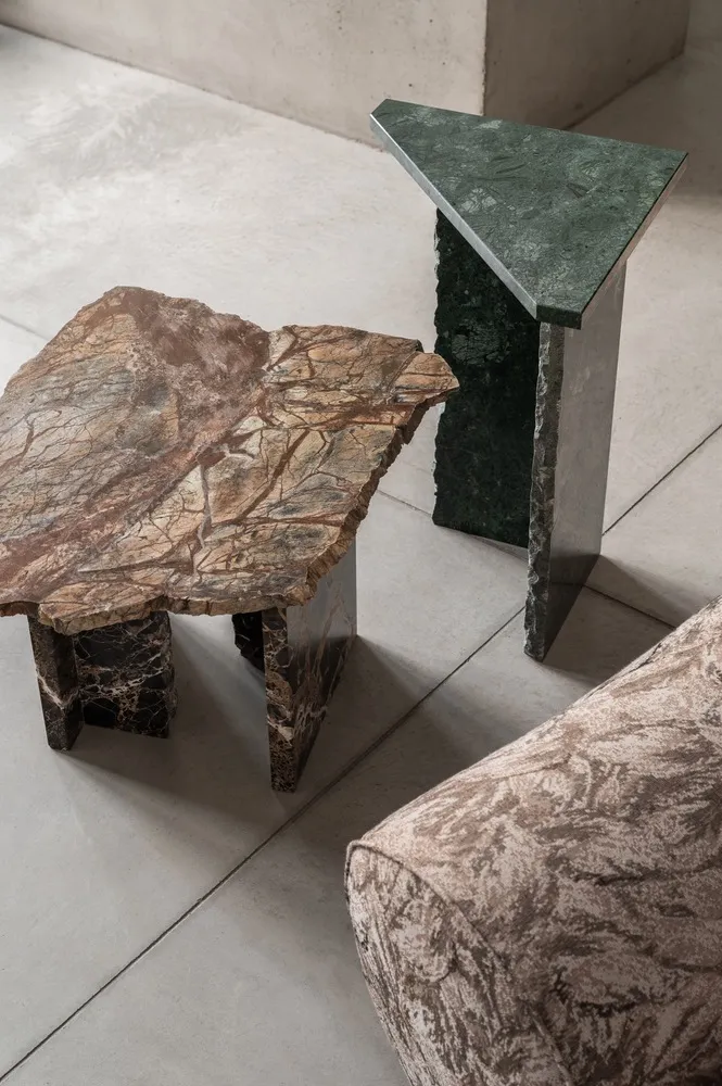 A modern interior design featuring marble side tables on a concrete floor.