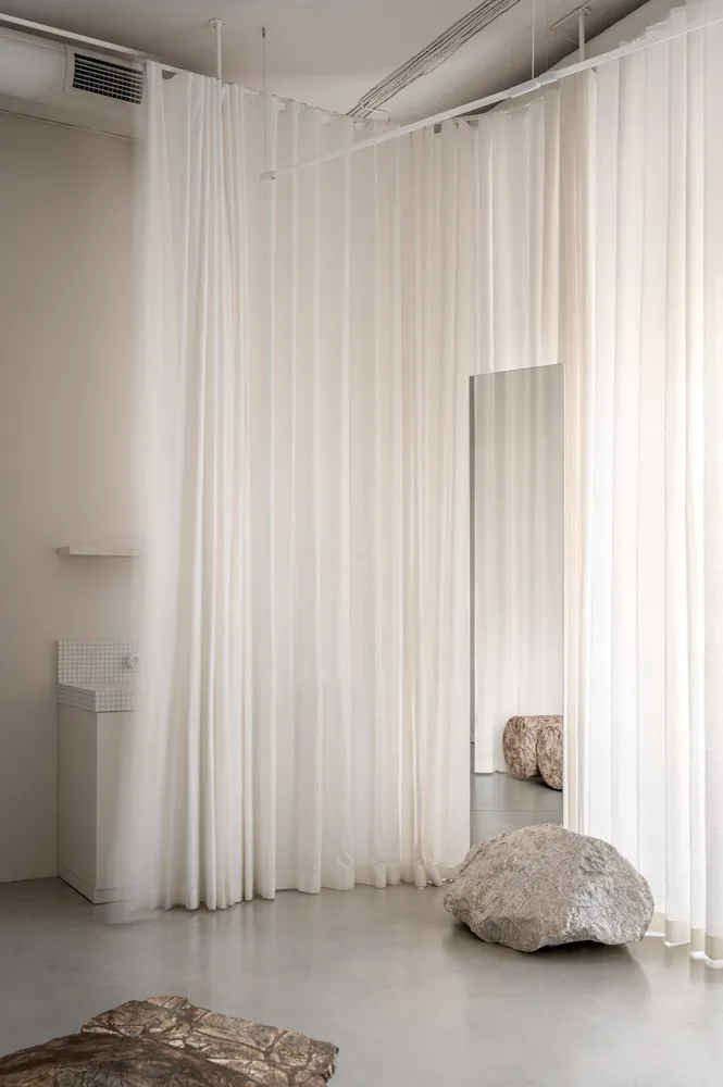A minimalist interior with textured curtains, rocks, and stone flooring.