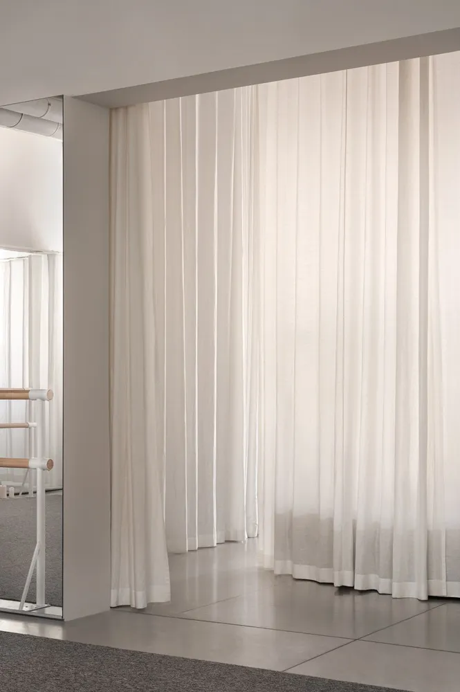 A minimalist interior with floor-to-ceiling white curtains.