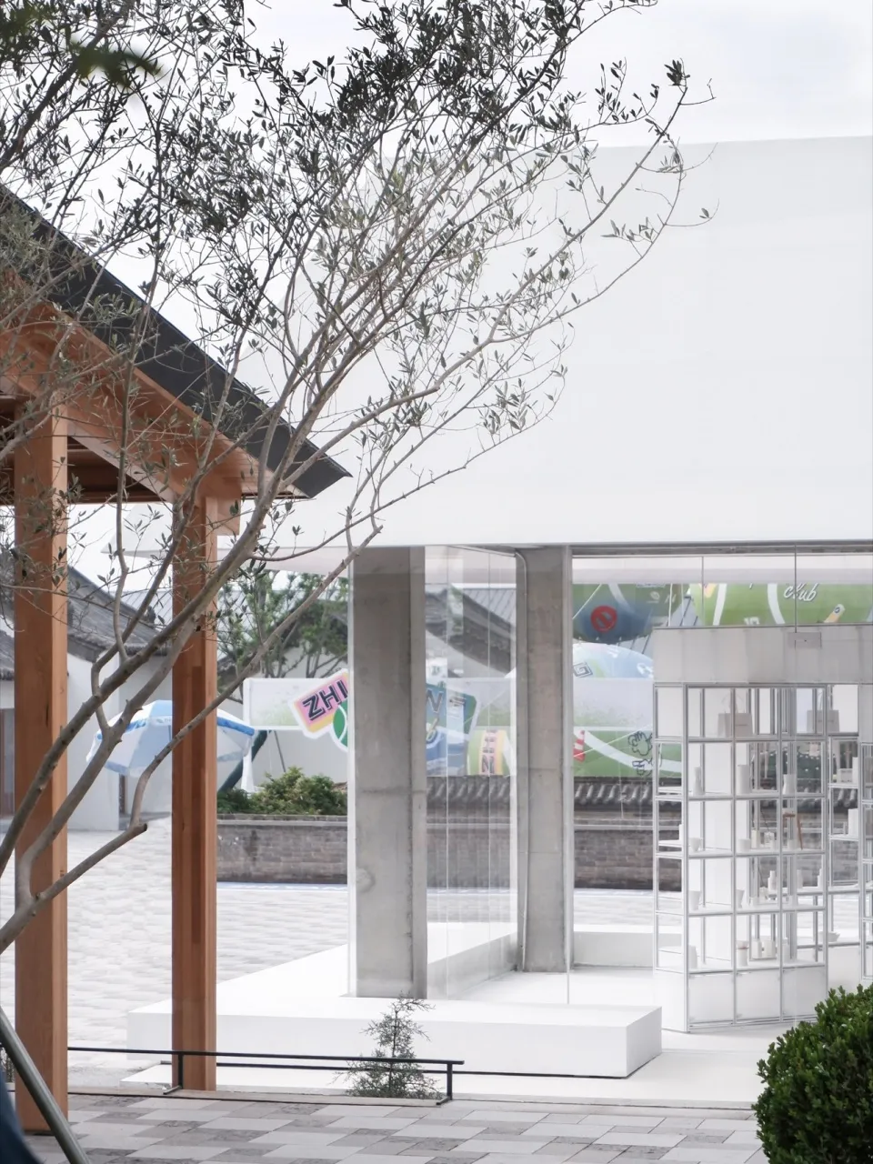 Modern glass and concrete storefront with plants and signage.